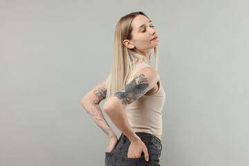 Fototapeta premium Portrait of beautiful tattooed woman on gray background