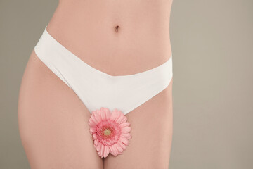 Gynecology. Woman in underwear with gerbera flower on grey background, closeup