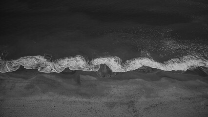 Grayscale of a wave crashing on the shore