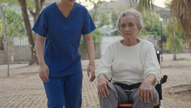Asian careful caregiver and patient, Nurse gives a pep talk to an elderly female patient in the garden in the evening. Health insurance.