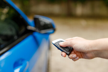 Womans hand pushing unlock button on car remote