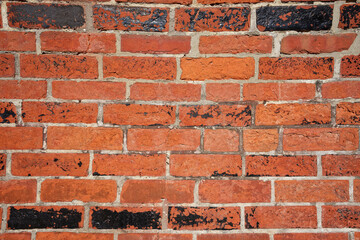 Weathered old red brick wall with peeling paint and cracks.