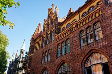 Fototapeta premium some people walking near a building and trees and buildings that have windows