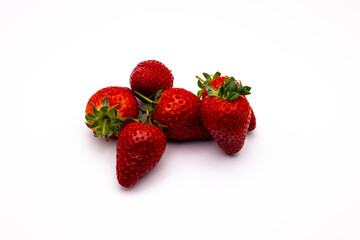 three ripe strawberries stacked against each other on a white surface