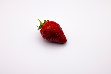 the ripe strawberry is on a white surface with a shadow