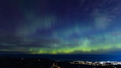 Aurora Australis or southern lights over the city of Dunedin, New Zealand; beautiful purple, pink...