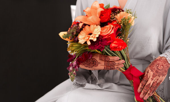 Hands, henna pattern and bouquet for wedding in studio with respect for tradition, faith and culture. Closeup, marriage and woman for walima or nikah ceremony with religious, flowers and romantic.