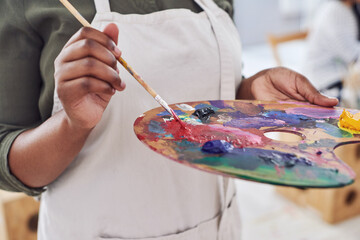 Person, hands and art palette in closeup for painting with sustainable materials for creative...