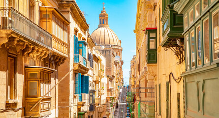 Sunny street in Valletta old town, Basilica of Our Lady of Mount Carmel on a background, Malta