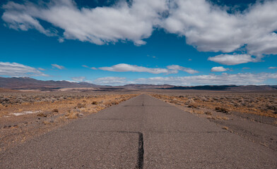 Deserted highway in an arid desert with a clear blue sky in Nevada