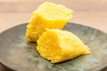 Traditional Brazilian pamonha served on a rustic plate, showcasing its vibrant yellow color and rich texture, perfect for cultural cuisine lovers.