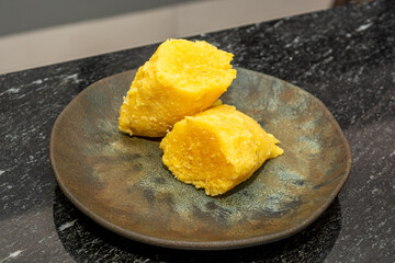Close-up of traditional Brazilian pamonha, a popular corn-based dish, served on a rustic plate against a granite countertop.