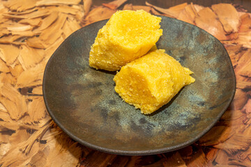 Traditional Brazilian pamonha served on a rustic plate, showcasing the rich, yellow color and texture of the corn-based delicacy.