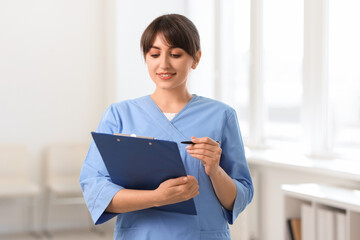 Portrait of smiling medical assistant with clipboard and pen in hospital