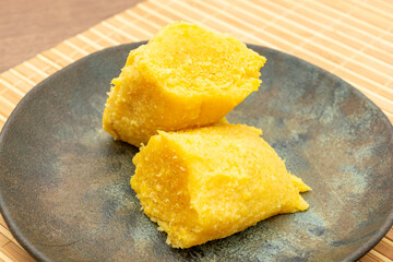 Delicious Brazilian pamonha made from sweet corn, served on a rustic plate. Traditional Latin American dish perfect for a savory snack or dessert.