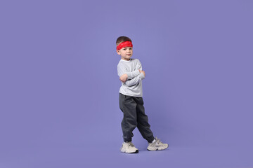 Happy little boy dancing on violet background