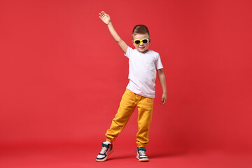 Happy little boy dancing on red background