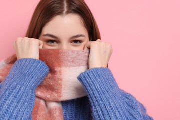 Beautiful woman in warm scarf on pink background, space for text