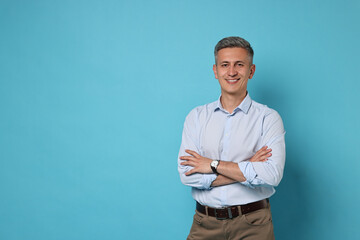 Portrait of happy man on light blue background, space for text