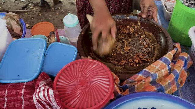 Preparing rujak petis. Rujak petis is traditional food from Java made from steamed mix vegetables, black sauce made from fried garlic, chillies, petis (black fermented shrimp paste) and ground peanuts