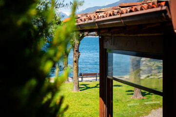 Lakeside view through greenery and rustic house