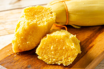 Traditional Brazilian pamonha, a sweet corn-based dish, delicately wrapped and served on a wooden...