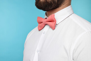 Man in shirt and bow tie on light blue background, closeup