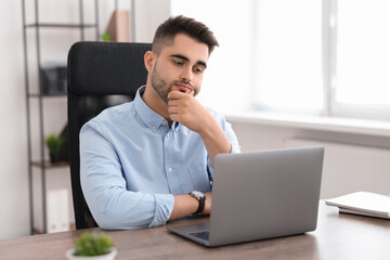 Fototapeta premium Young programmer working with laptop in office
