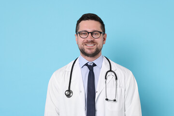 Fototapeta premium Portrait of smiling doctor on light blue background