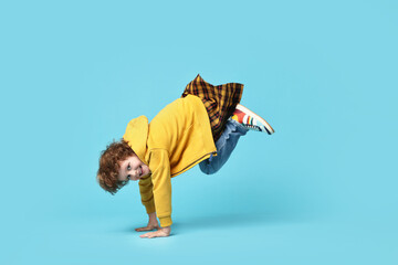 Happy little boy dancing on light blue background