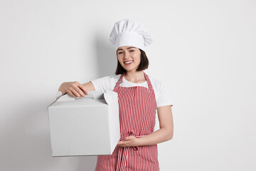 Happy confectioner with cake box on light grey background