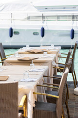 Outdoor dining tables by marina with yachts
