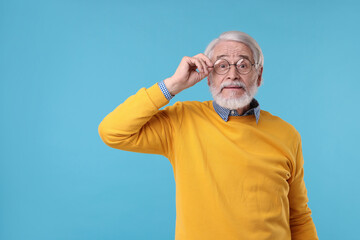 Portrait of stylish grandpa with glasses on light blue background