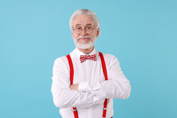 Portrait of stylish grandpa with glasses and bowtie on light blue background