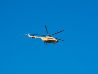 White helicopter against cloudless blue sky.