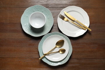 Beautiful ceramic dishware and cutlery on wooden table, flat lay