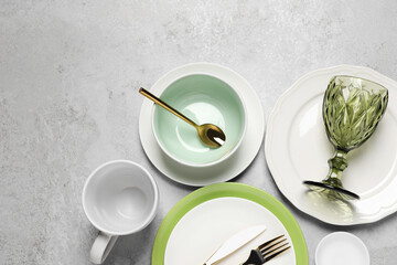 Beautiful ceramic dishware, cup, glass and cutlery on light grey table, flat lay