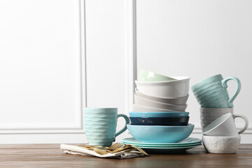 Beautiful ceramic dishware, cups and cutlery on wooden table, space for text