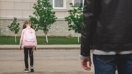 Fototapeta premium Father with cute little daughter see off to school elementary class outdoor near school building. Child pupil with backpack going dad with love before going classroom
