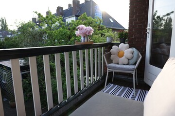 Different plants on railings and chair at cozy balcony outdoors