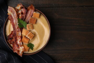 Delicious lentil soup with bacon and parsley in bowl on wooden table, top view. Space for text