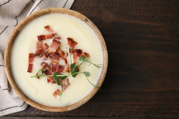 Delicious potato soup with bacon and microgreens in bowl on wooden table, top view. Space for text