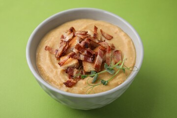 Delicious lentil soup with bacon and croutons on green background