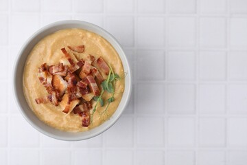 Delicious lentil soup with bacon and croutons on white tiled table, top view. Space for text