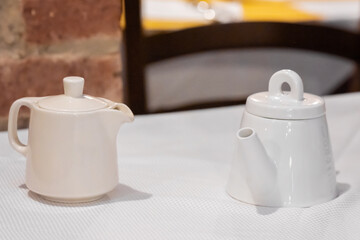 Two teapots on table with brick wall background
