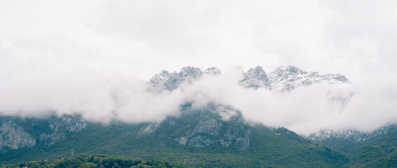 Snow-capped mountains with clouds and greenery