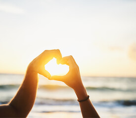 Hands, heart and couple on beach with sunset for love with vacation or holiday with lens flare on...