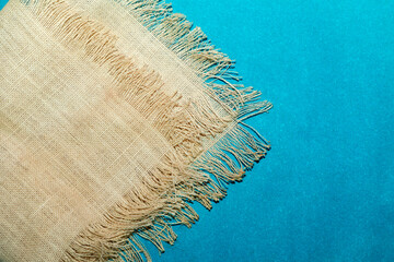 Brown burlap hemp cloth on blue background, text place, copy space. Sackcloth fabric as background.