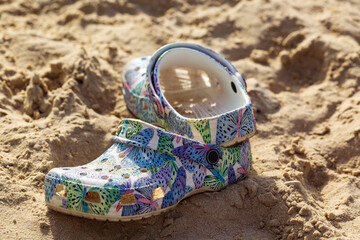 Colorful childrenâ€™s shoe with a pattern of leaves and geometric shapes lying abandoned on a...