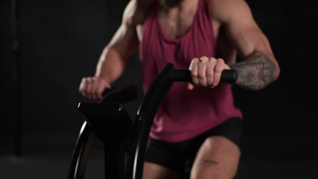 Close up of a man exercising on elliptical cross-trainer machine, wearing activewear. Routine workout for physical and mental health.